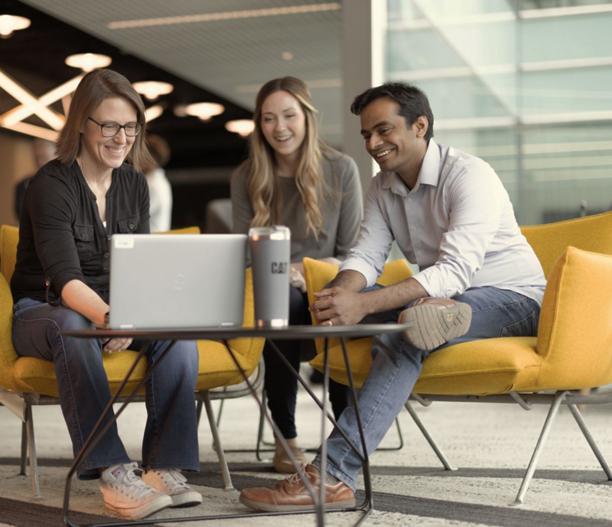a group of people sitting in chairs and looking at a laptop