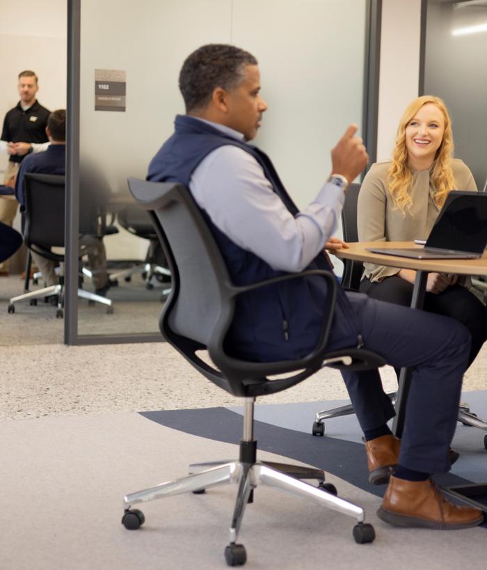 a person and person sitting at a table with laptops