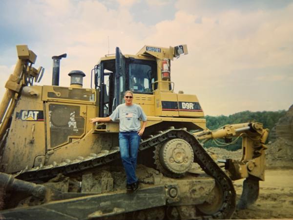 a person standing on a large yellow tractor