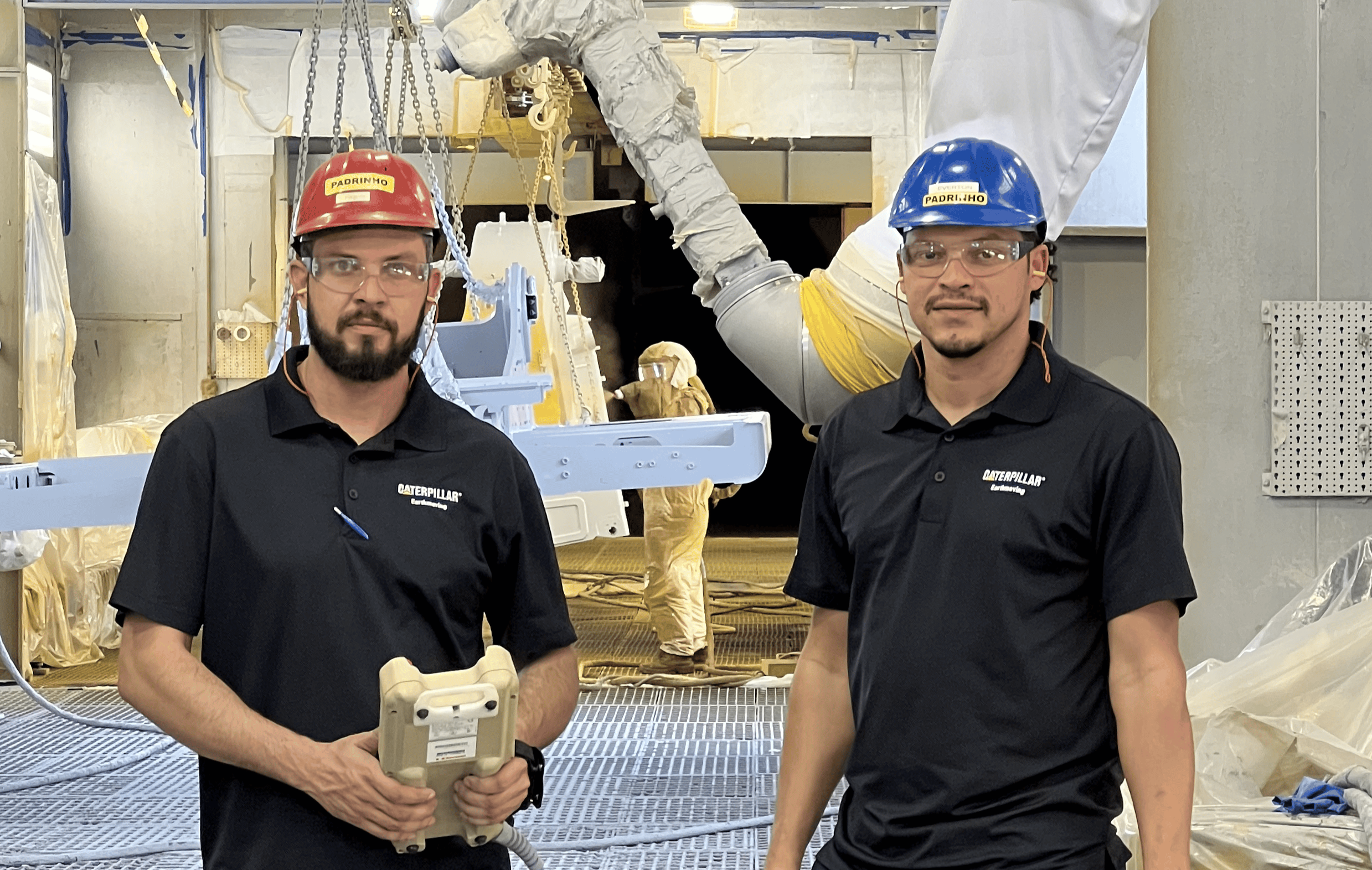 two men wearing hard hats and holding objects