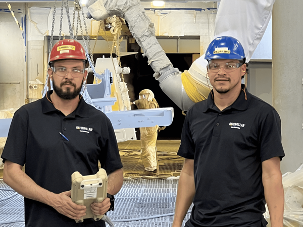 two men wearing hard hats and holding objects