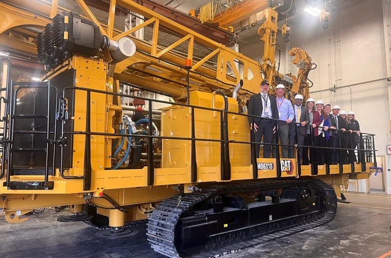 a group of people standing on a yellow machine