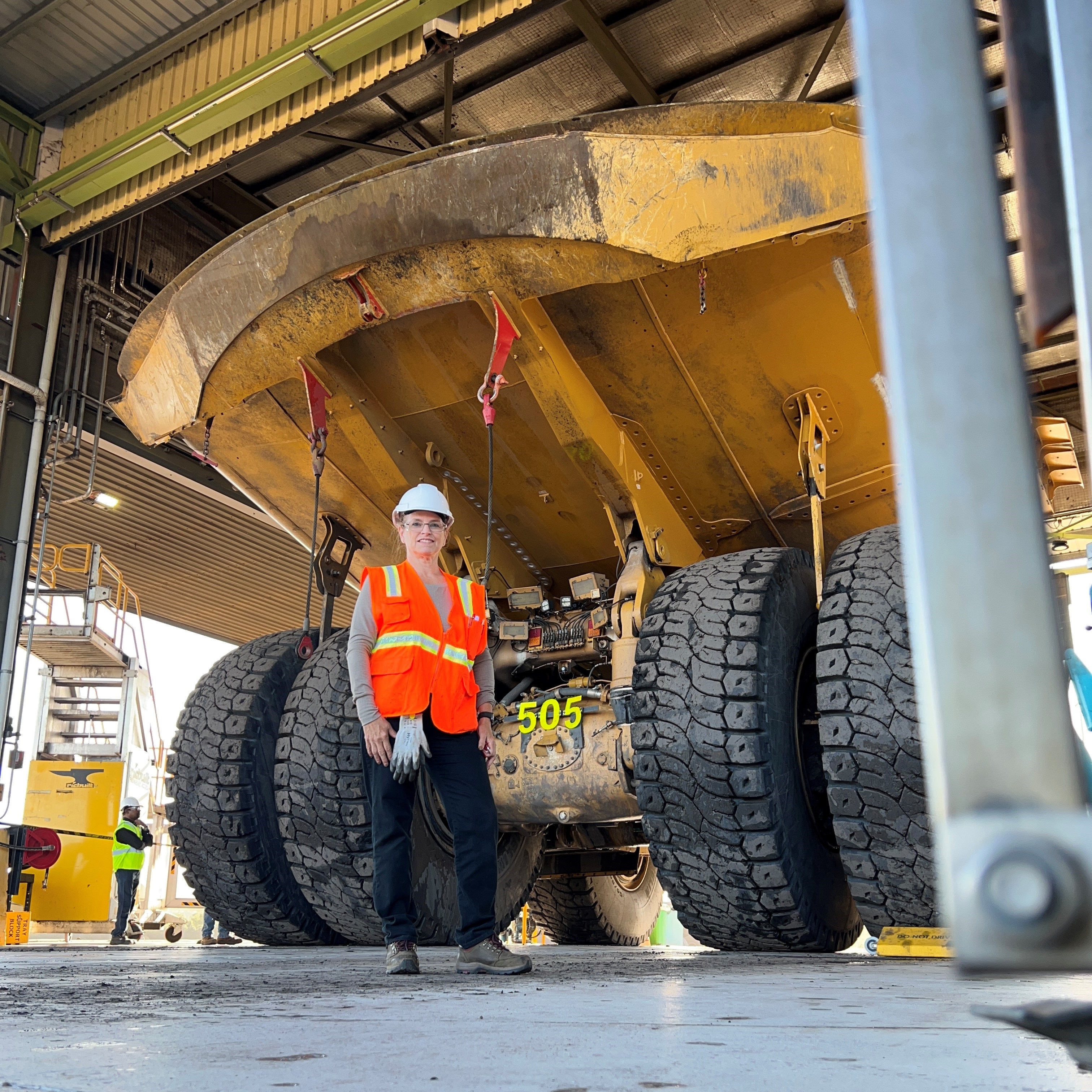 a person in a hard hat standing in front of a large truck