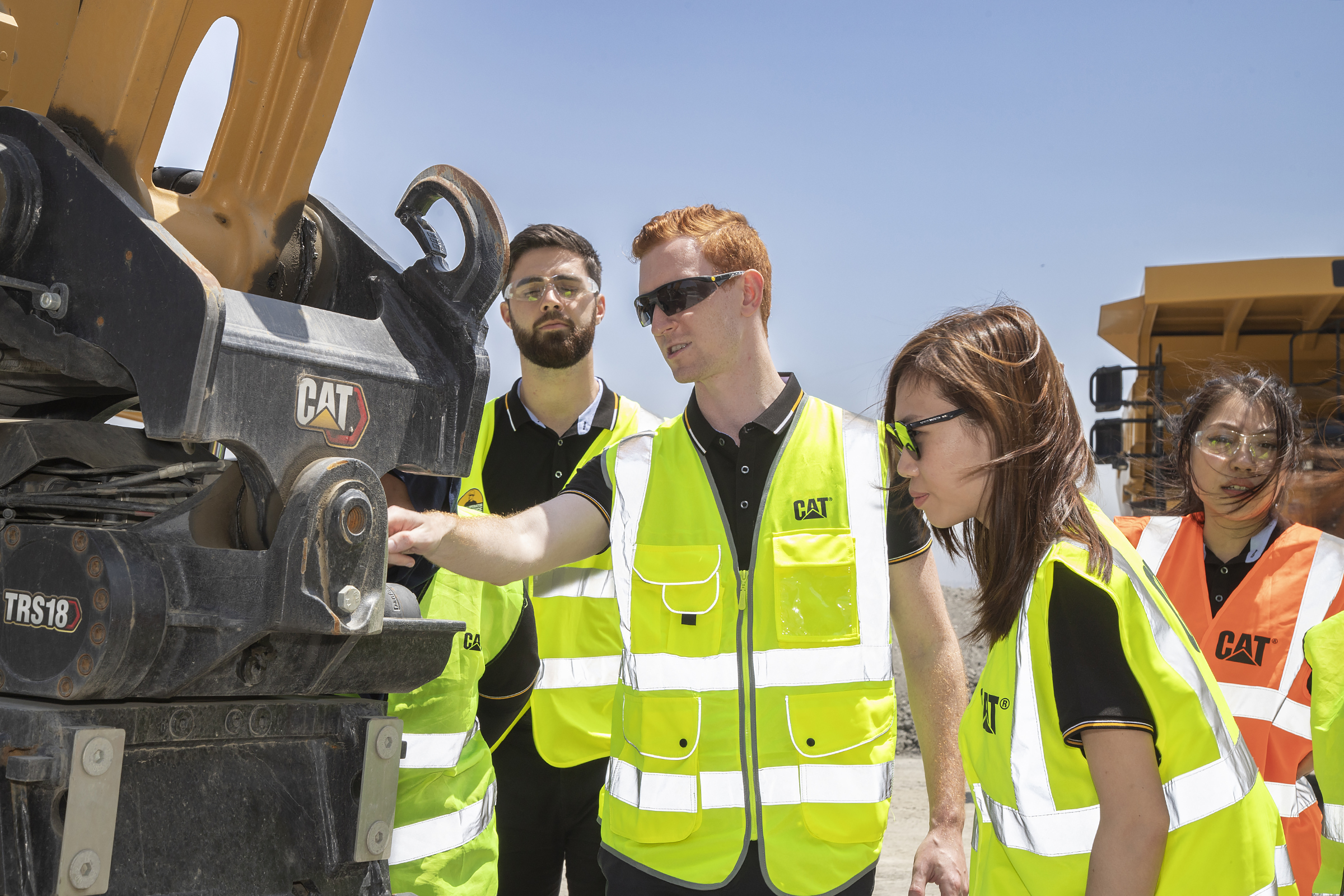 a group of people in safety vests looking at a machine