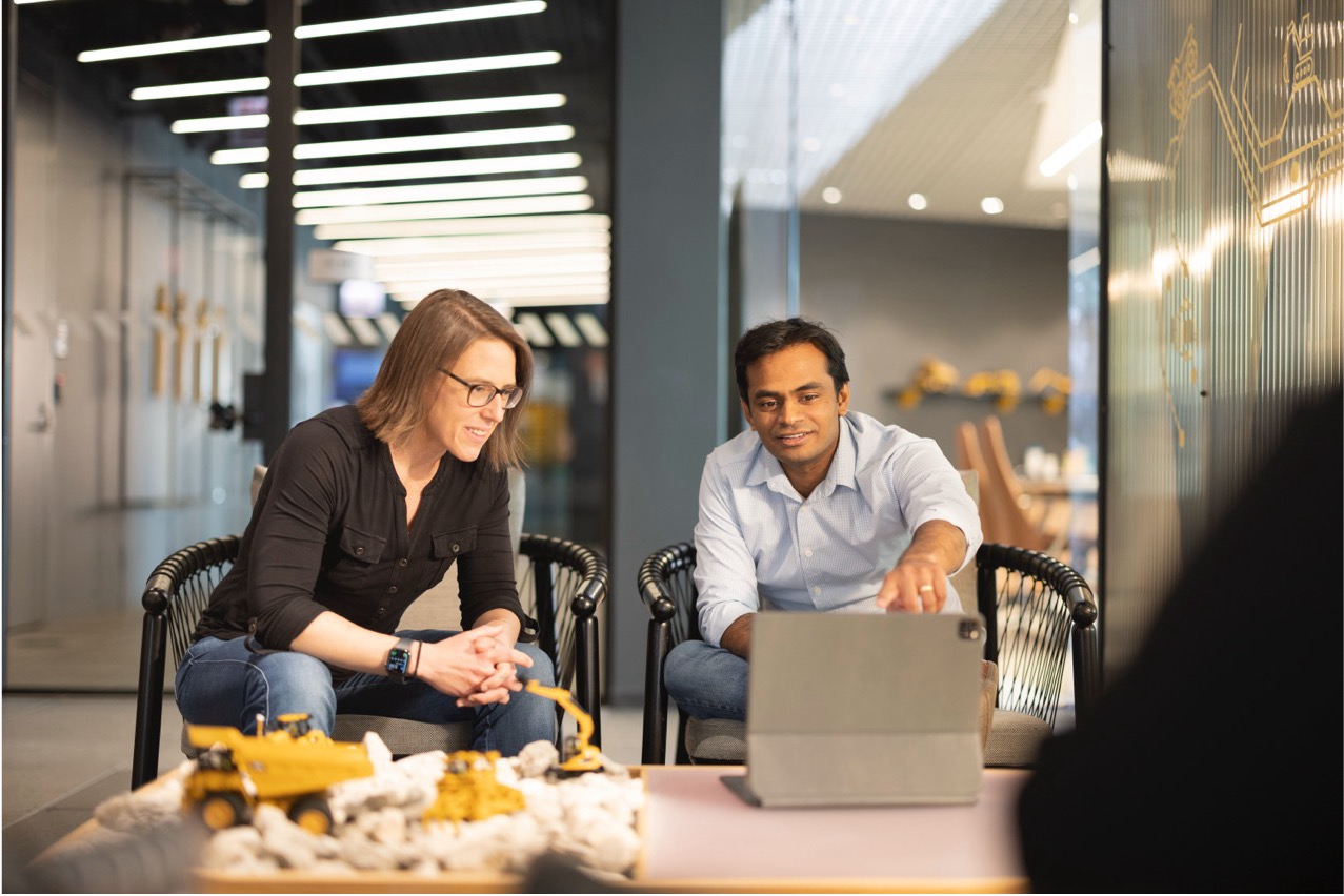 a person and person sitting in chairs looking at a laptop
