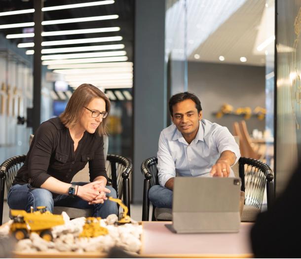 a person and person sitting in chairs looking at a laptop