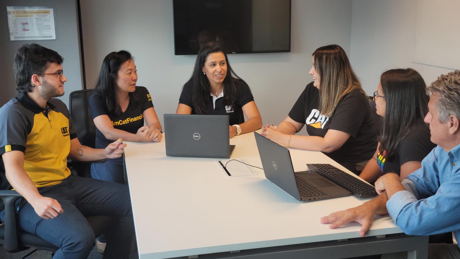a group of women sitting around a table with laptops