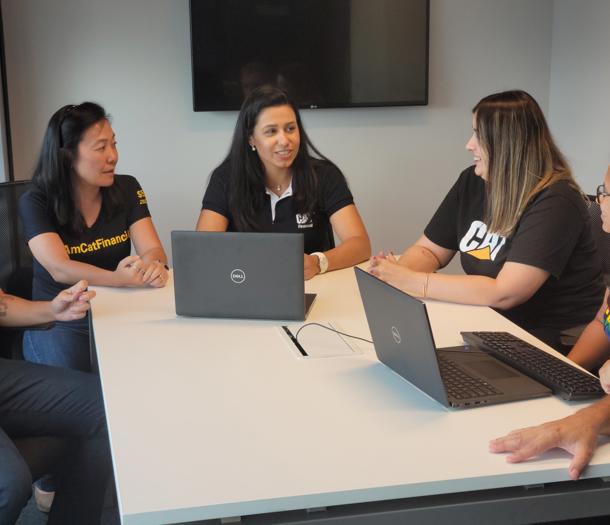 a group of women sitting around a table with laptops